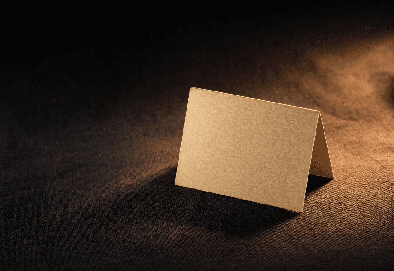 A folded cream paper note on dark linen, lit by warm tungsten light.